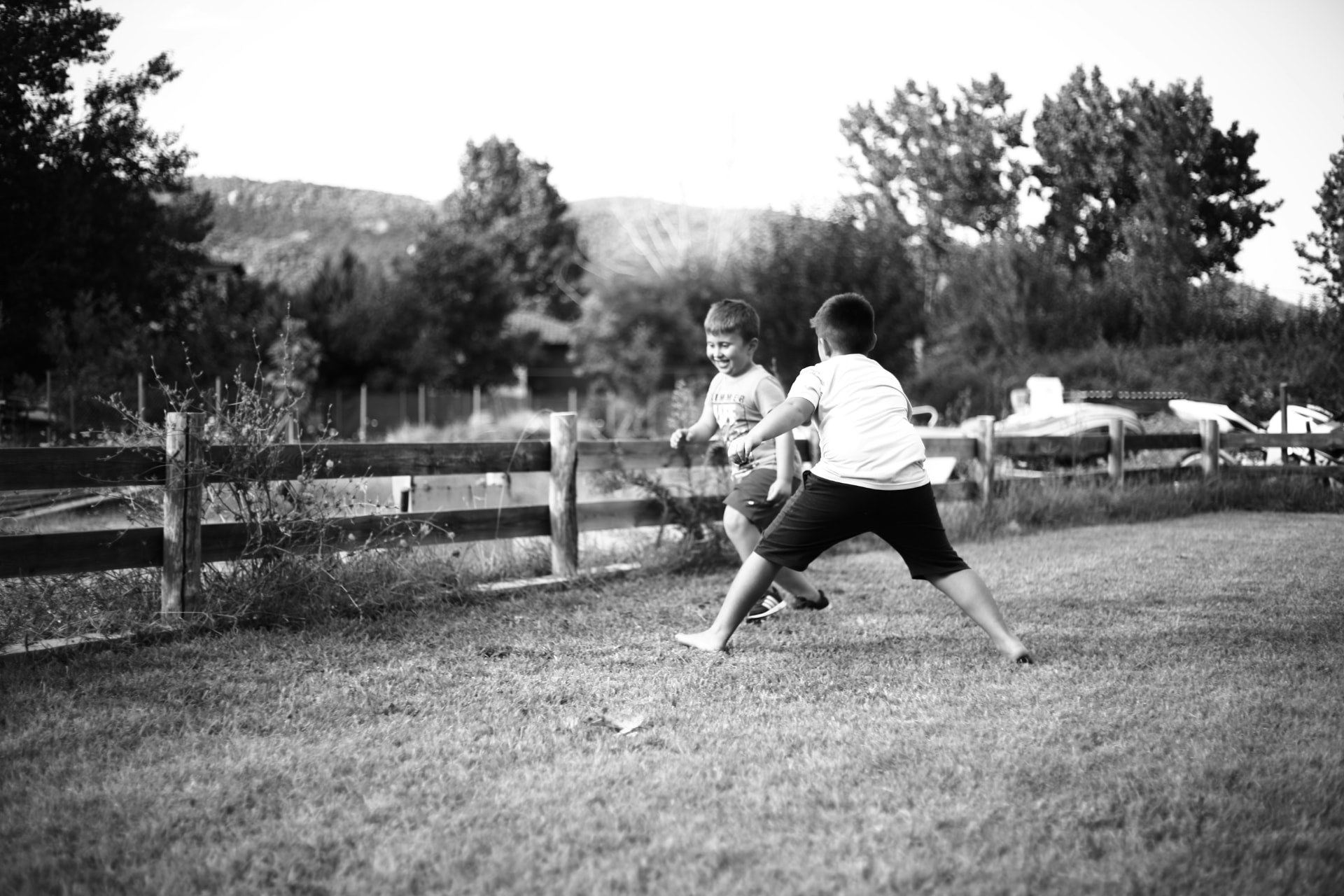 Two children laughing and chasing each other across a grassy yard